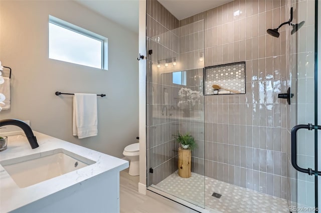 full bath with double vanity, a sink, toilet, and a shower stall