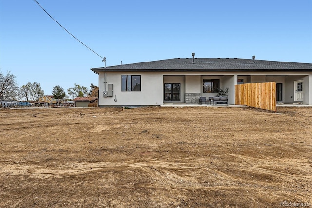 back of property with a patio, a shingled roof, and stucco siding