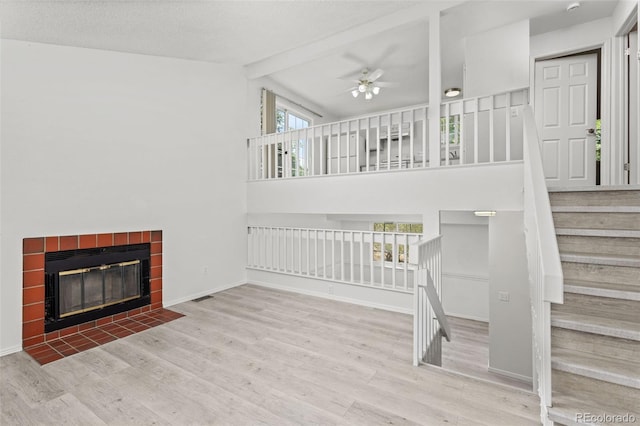 living room featuring baseboards, a tiled fireplace, ceiling fan, wood finished floors, and stairs