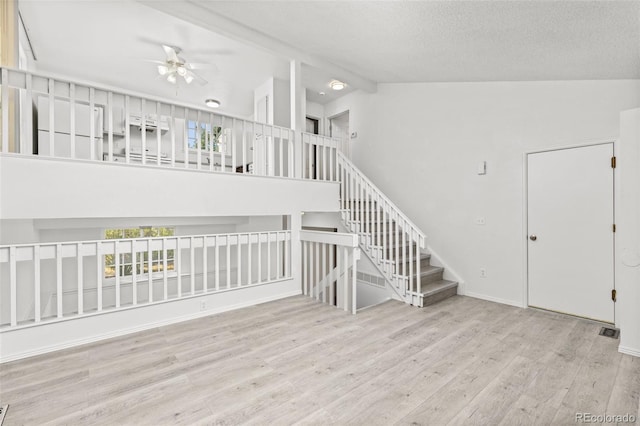 unfurnished room with ceiling fan, a textured ceiling, wood finished floors, high vaulted ceiling, and stairs