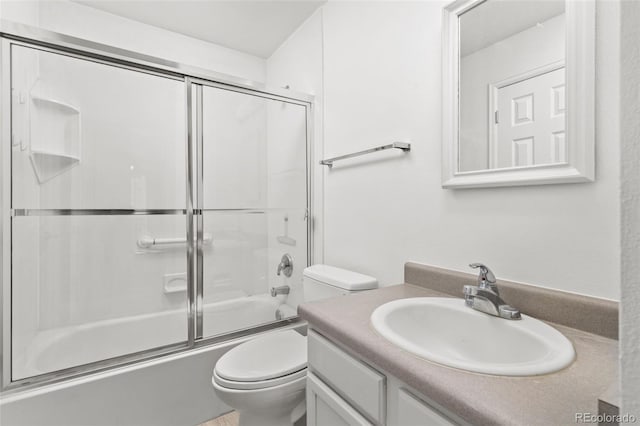 full bathroom featuring toilet, combined bath / shower with glass door, and vanity