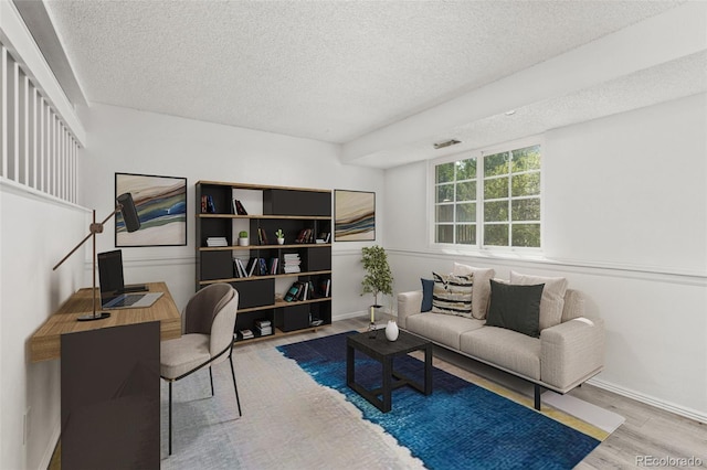 interior space with a textured ceiling, wood finished floors, and baseboards