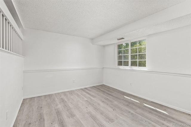 empty room with a textured ceiling, baseboards, and wood finished floors