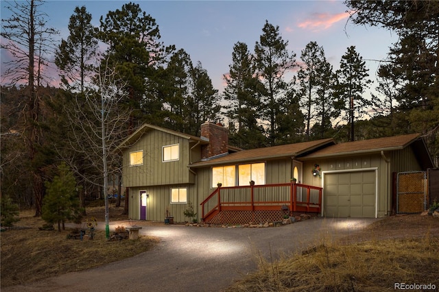 tri-level home with board and batten siding, a garage, driveway, and a chimney