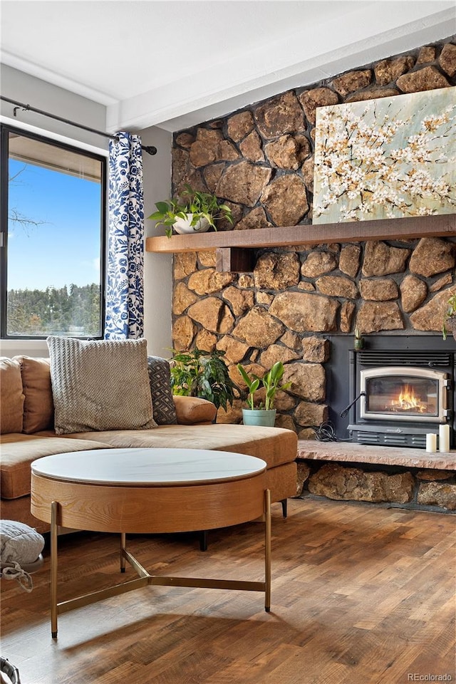 living area with a stone fireplace and wood finished floors