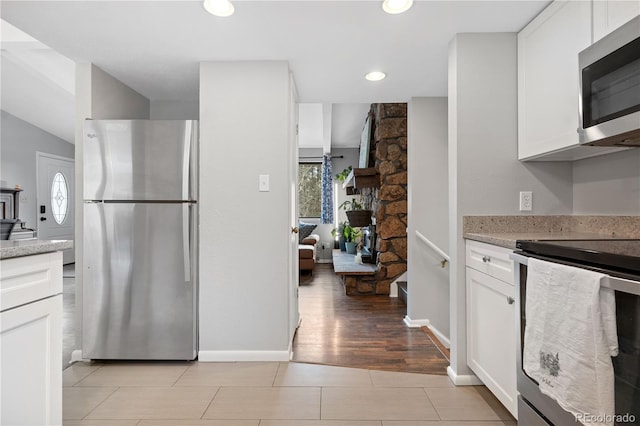 kitchen with light stone counters, recessed lighting, stainless steel appliances, white cabinets, and baseboards