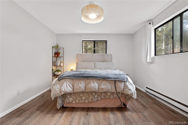 bedroom featuring a baseboard heating unit, wood finished floors, and baseboards