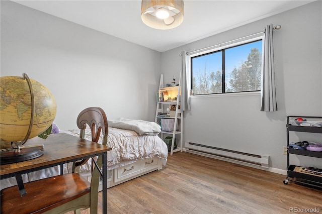 bedroom featuring light wood finished floors, baseboard heating, and baseboards