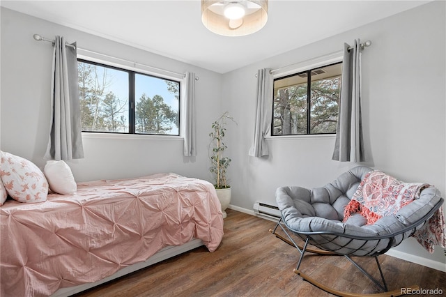 bedroom with a baseboard radiator, baseboards, and wood finished floors