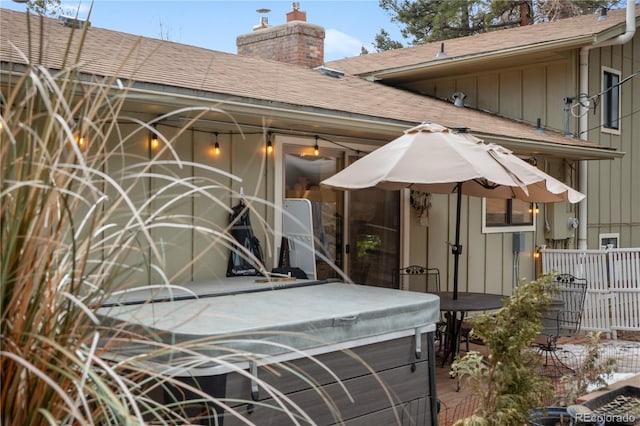 exterior space with a shingled roof, fence, board and batten siding, and a chimney