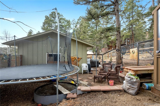 rear view of house featuring a trampoline and fence