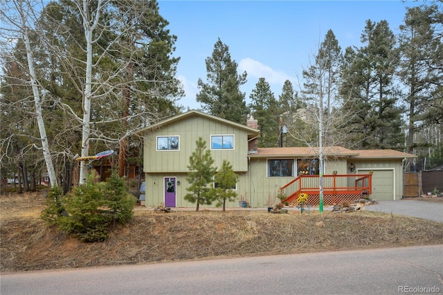 split level home featuring an attached garage, a chimney, and driveway