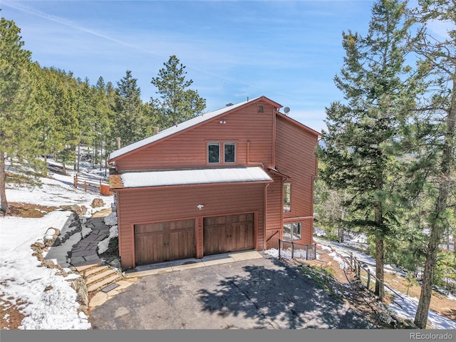 27100 Molly Dr, Conifer, CO 80433 - view of snow covered exterior featuring asphalt driveway and a garage