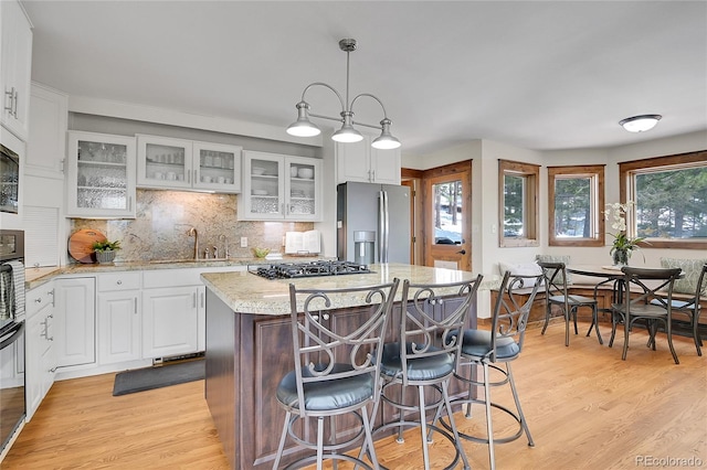 27100 Molly Dr, Conifer, CO 80433 - kitchen with stainless steel appliances, a sink, white cabinets, light stone counters, and light wood-style floors