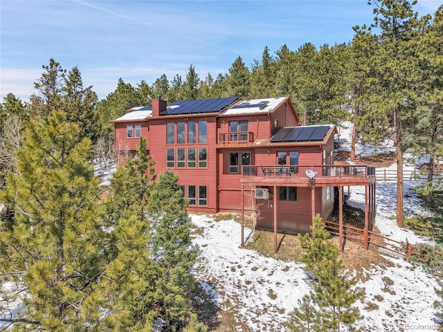 27100 Molly Dr, Conifer, CO 80433 - snow covered house featuring roof mounted solar panels, a chimney, and a wooden deck