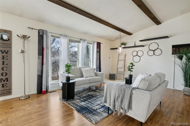 living room with vaulted ceiling with beams, hardwood / wood-style flooring, and a textured ceiling