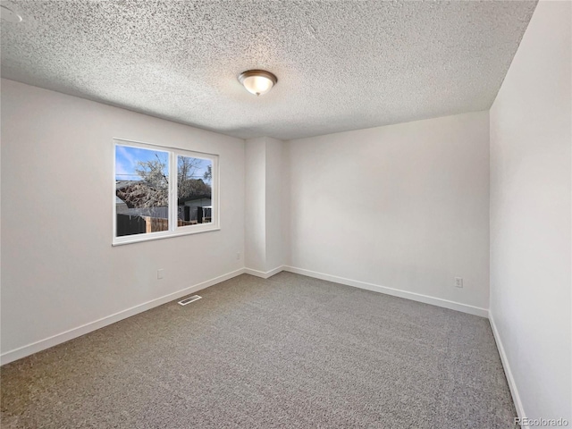 carpeted spare room with a textured ceiling, visible vents, and baseboards