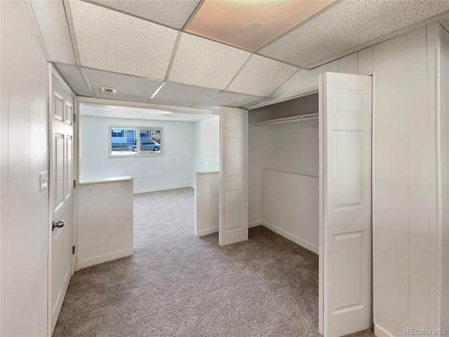 unfurnished bedroom with a closet, carpet flooring, a paneled ceiling, and baseboards