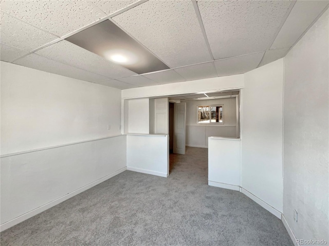 carpeted spare room featuring a paneled ceiling and baseboards