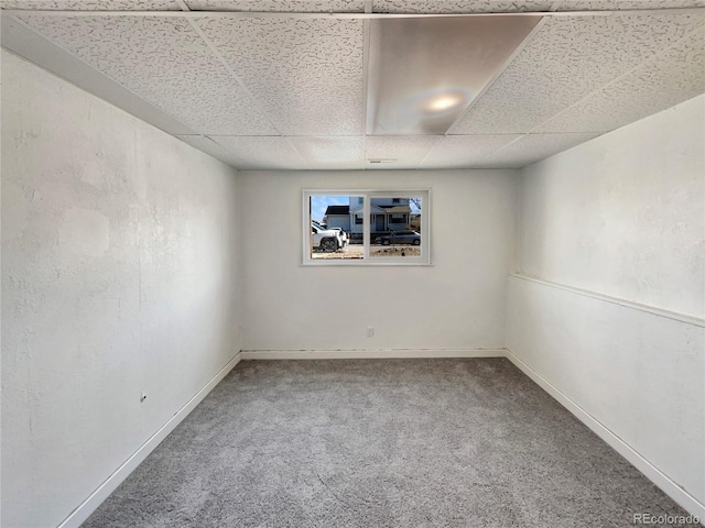 carpeted spare room with a drop ceiling and baseboards