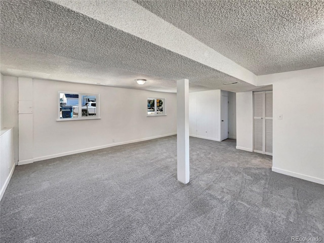 basement featuring a textured ceiling, baseboards, and carpet flooring