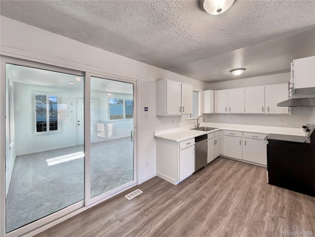 kitchen with a sink, light wood-style floors, light countertops, dishwasher, and wall chimney exhaust hood