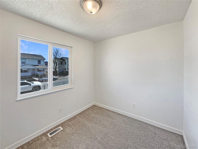 spare room featuring baseboards, visible vents, a textured ceiling, and carpet flooring