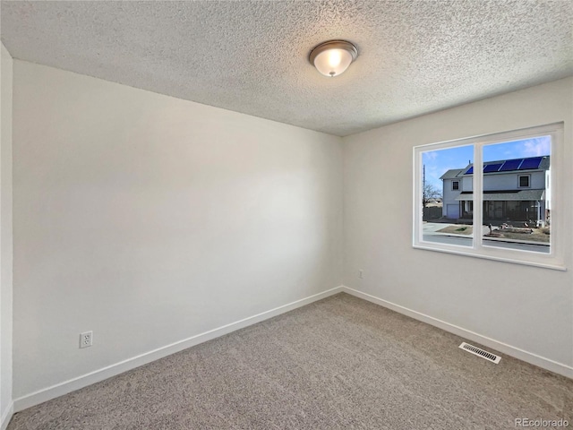 carpeted spare room with visible vents, baseboards, and a textured ceiling