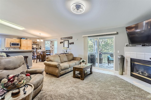 tiled living room featuring lofted ceiling, a fireplace, and a chandelier