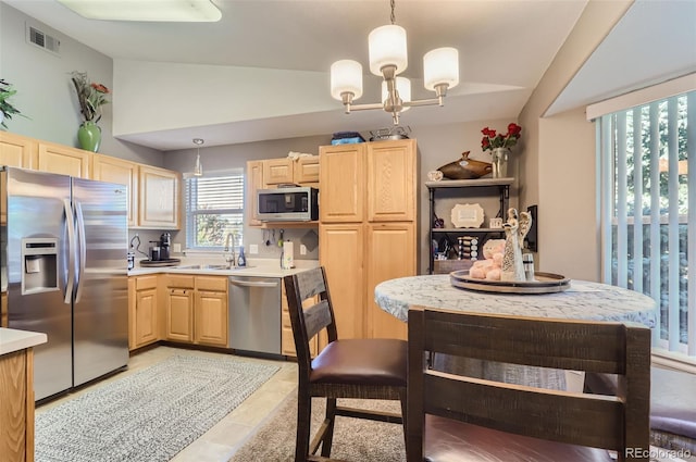 kitchen with light brown cabinets, light tile patterned floors, stainless steel appliances, lofted ceiling, and decorative light fixtures