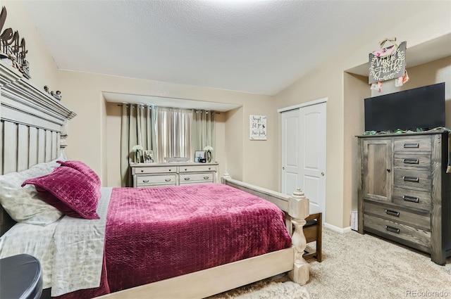 carpeted bedroom with vaulted ceiling, a closet, and a textured ceiling