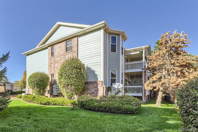 view of side of home with a balcony and a yard