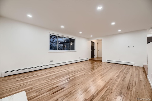 unfurnished living room featuring baseboard heating and light hardwood / wood-style floors