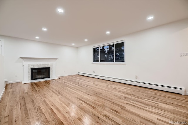 unfurnished living room featuring a fireplace, light hardwood / wood-style flooring, and baseboard heating