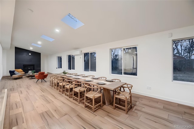 dining space featuring light wood-type flooring and lofted ceiling with skylight