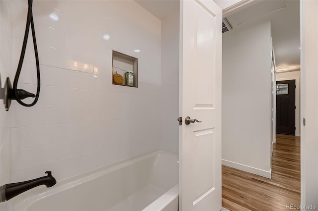 bathroom with tiled shower / bath combo and hardwood / wood-style flooring