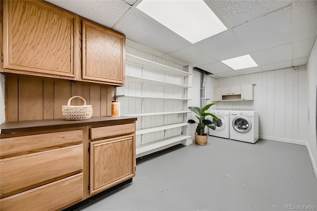 laundry area featuring washing machine and dryer, wood walls, and cabinets