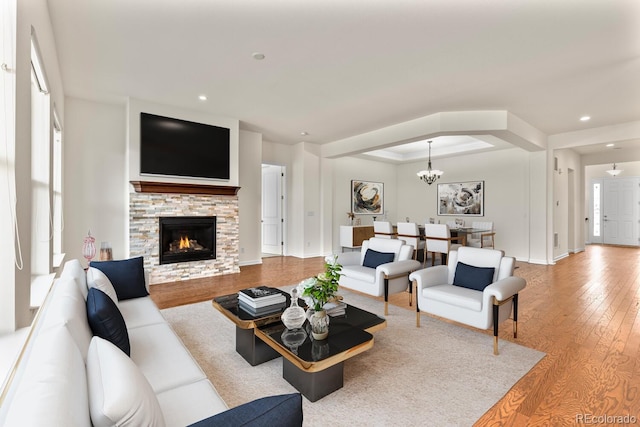 living room with hardwood / wood-style flooring, a tray ceiling, a fireplace, and a chandelier