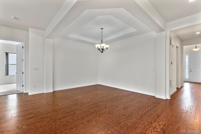 unfurnished room with dark hardwood / wood-style flooring, a raised ceiling, and a chandelier