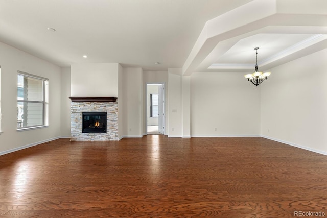 unfurnished living room featuring a fireplace, ornamental molding, dark hardwood / wood-style floors, and a notable chandelier