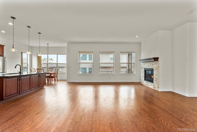 unfurnished living room featuring a stone fireplace and light hardwood / wood-style floors