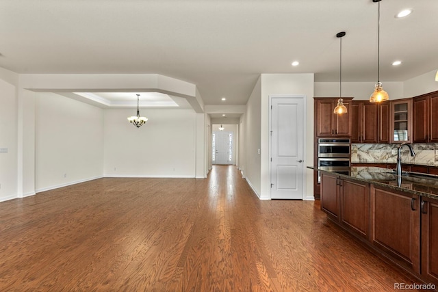 kitchen featuring dark hardwood / wood-style flooring, sink, dark stone counters, and decorative light fixtures