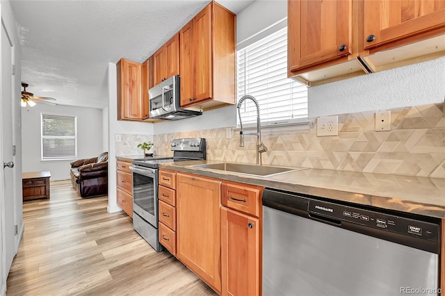 2791 Quarterland St, Strasburg, CO 80136 - kitchen with stainless steel appliances, a sink, light wood-type flooring, backsplash, and ceiling fan
