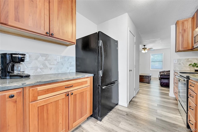 2791 Quarterland St, Strasburg, CO 80136 - kitchen with freestanding refrigerator, stainless steel range, a ceiling fan, light wood-style flooring, and decorative backsplash