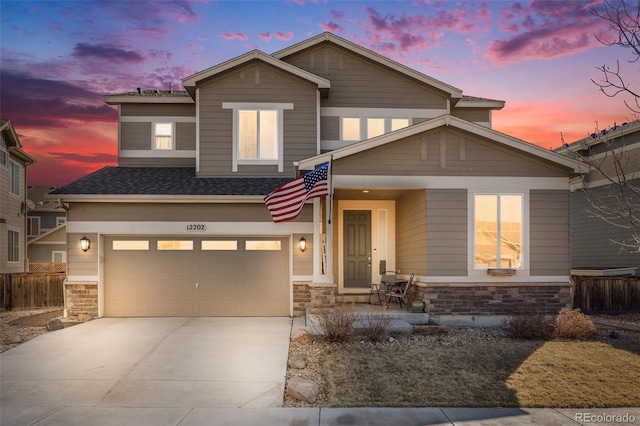 view of front of house featuring a garage, stone siding, driveway, and fence