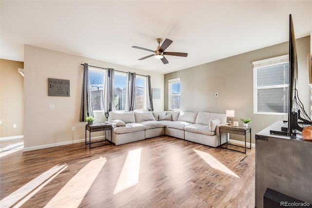 living area featuring light wood-style floors, baseboards, and a ceiling fan