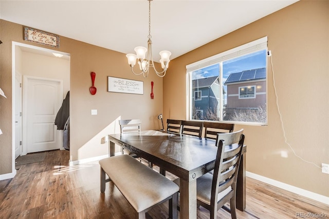 dining room featuring light wood-style flooring, a chandelier, and baseboards