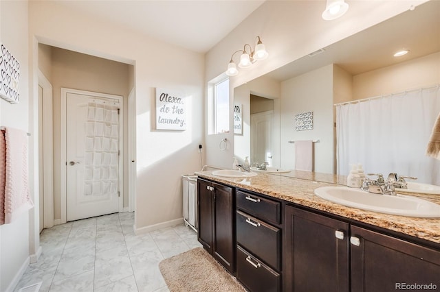 full bath featuring double vanity, marble finish floor, baseboards, and a sink