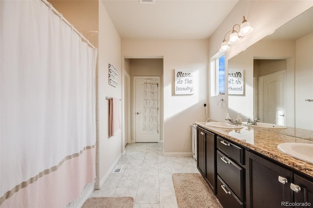 bathroom featuring double vanity, visible vents, baseboards, marble finish floor, and a sink