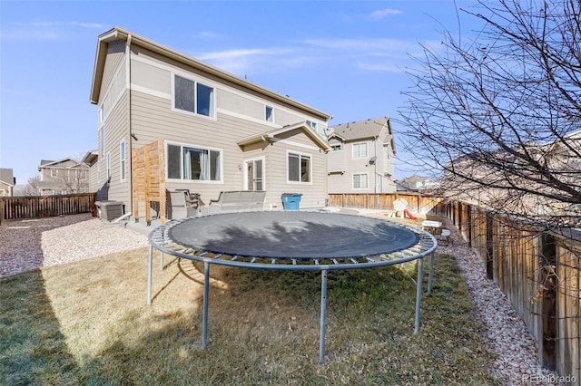 rear view of house featuring a trampoline, a fenced backyard, and central air condition unit